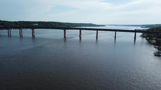 Aerial drone video of a bridge crossing the Mississippi River between Illinois and Iowa near quad cities of Davenport and Moline with cars crossing over the bridge as the drone flies towards it.