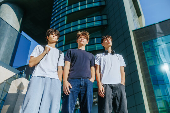 Confident teenage boys standing together outdoors near a modern city building