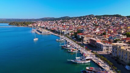 Cinematic aerial footage of Argostoli, the charming capital of Kefalonia Island in Greece. The clip captures the picturesque harbor, colorful waterfront houses, and boats gliding over the Ionian Sea.