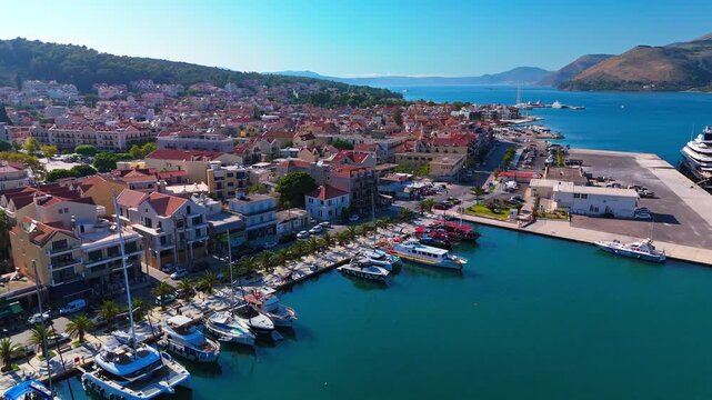 Cinematic aerial footage of Argostoli, the charming capital of Kefalonia Island in Greece. The clip captures the picturesque harbor, colorful waterfront houses, and boats gliding over the Ionian Sea.