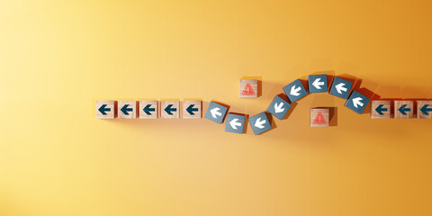 Wooden blocks with arrow icons changing direction to avoid red warning symbol on yellow background. Concept of business strategy, decision making, and problem solving.
