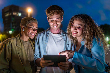 Diverse friends sharing content on tablet at night