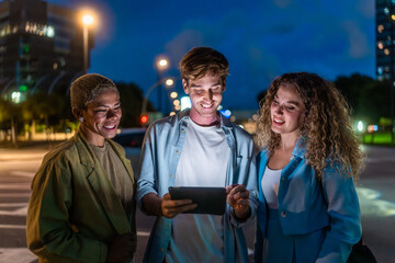 Diverse friends connecting night city with tablet