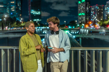 Diverse young couple talking on city bridge at night
