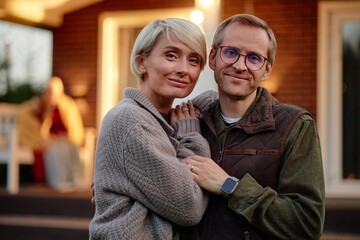 Caucasian middle aged woman and Caucasian middle aged man standing close together outdoors smiling...