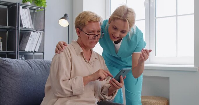 Senior patient uses smartphone with caregiver guidance. A nurse provides support, showing technology apps for messages and medication reminders at home. Theme learning and connected care.