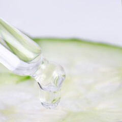 Dropper and droplet in focus, cucumber slice blur, clean beauty product concept, 1:1.