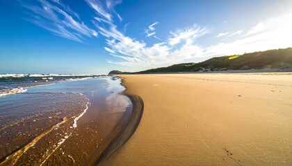 Sunny beach scene with sand, ocean, and partly cloudy sky