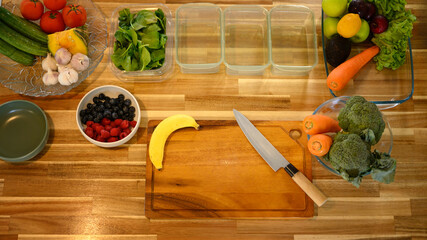 Above shot fresh vegetables and fruits neatly arranged in glass containers on a wooden kitchen...