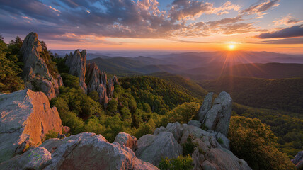 Dramatic sunset over a rocky mountain range with lush green forest below