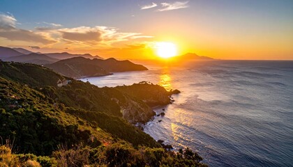 Golden sunset illuminates coastline and rolling hills beside tranquil ocean