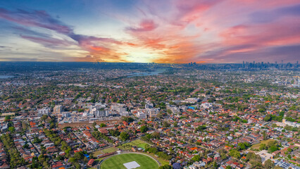 Naklejka premium Panorama Sunset aerial drone view of western Sydney Suburbs of Canterbury Burwood Ashfield Marrickville Campsie with Houses roads and parks in Sydney New South Wales NSW Australia