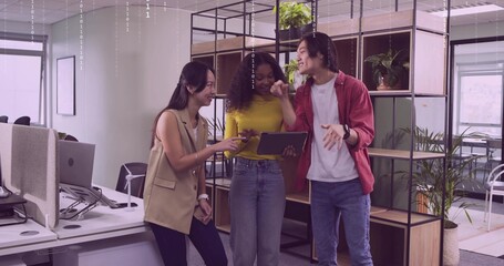 Discussing project using tablet by three colleagues in modern office with shelving, desks, monitors