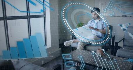 Viewing AR interface Indian man holding smartphone on gray sofa in modern office lounge, copy space