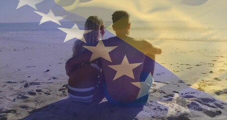 Sitting couple wearing swimwear gazing toward horizon at sandy beach waters edge, with flag overlay