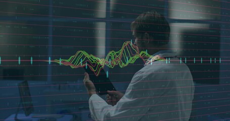 Scientist wearing lab coat holding tablet analyzing floating line chart inside lab with stations