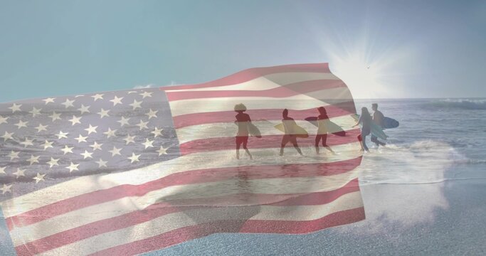Walking five surfers with surfboards entering surf at dawn beach, with American flag overlay