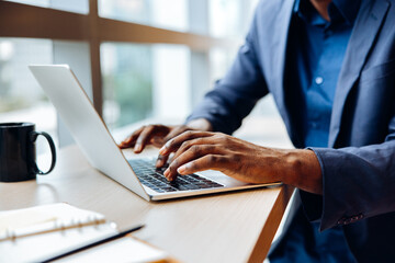 Professional working at a desk using a laptop with hands on the keyboard