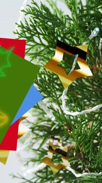 Animation of neon christmas bells over christmas decoration and branches