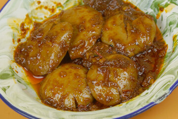 Authentic Indonesian cuisine, spicy jengkol or dog fruit cooked in Balado sauce, served on a classic enamel plate with a green and white pattern.