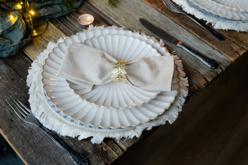 Elegant crockery on table. Festive table setting with white plates decorated napkin and golden ring.