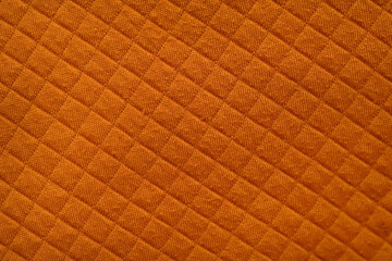 Obraz premium Close-Up of Orange Quilted Fabric with Diamond Stitch Pattern