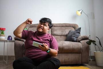 Excited Gamer Celebrates Mobile Game Victory With Fist Pump at Home