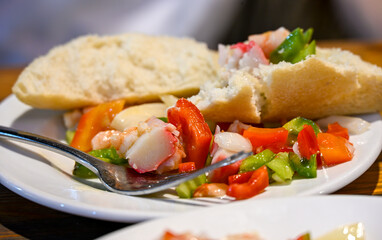 Plate of seafood salad, known locally as salpicón de marisco, a popular Spanish tapa made with crab, octopus, peppers, and onions, served with fresh bread.