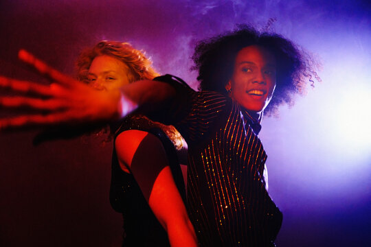 Joyful friends dancing together under neon lights at a nightclub