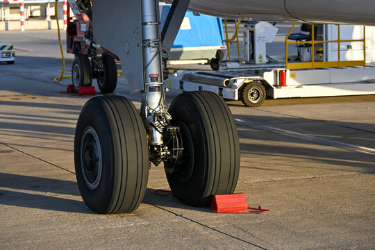Close-up of an aircraft landing gear with chocks securing the wheels on the airport tarmac.
