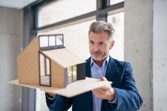 Mature architect examining model house in office