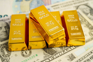 Gold bars on US dollar banknote money, finance trading investment business currency concept.