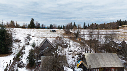 A tranquil winter panorama of Beskid Mały in southern Poland, where snowy meadows meet evergreen forests and rolling mountain hills under a serene, cloud-streaked sky.
