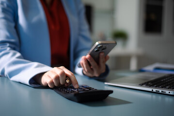 Woman counting coins on calculator taking from the piggy bank. hand holding pen working on calculator to calculate on desk
