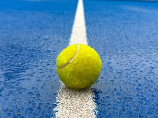 Blue paddle padel tennis court close up after rain. Tennis or paddle ball on the wet surface of the artificial grass court. Off season. Not playable.Matches are postponed or cancelled due to weather. 
