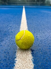 Blue paddle padel tennis court close up after rain. Tennis or paddle ball on the wet surface of the artificial grass court. Off season. Not playable.Matches are postponed or cancelled due to weather. 
