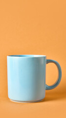 Blue ceramic mug on orange background expressing vibrant morning energy. Concept of cafe advertising, beverage branding, and lifestyle design with mockup simplicity.