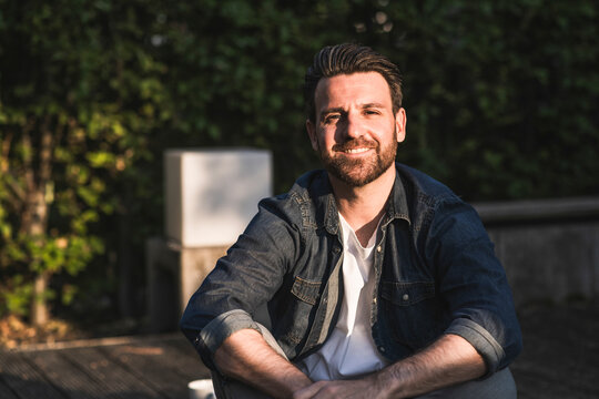 Happy man with beard sitting on porch