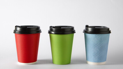 Three colorful takeaway coffee cups with black lids on white background for branding. Concept of beverage packaging, product lineup, mockup design for cafe and catering industry visuals.