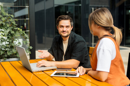 Colleagues discussing business planning with laptop outdoors at office