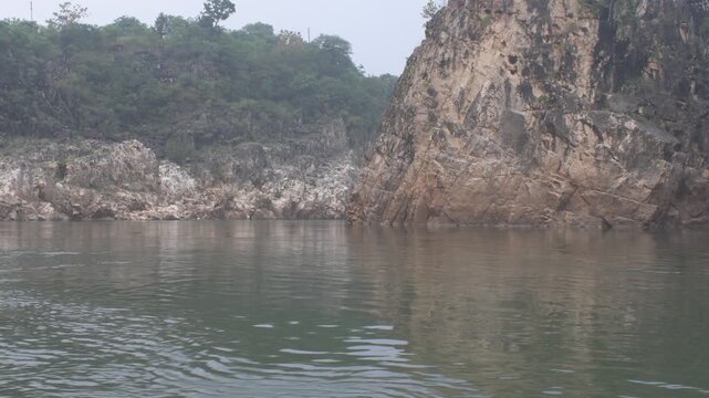 natural marble rock formations rising along the river at 'bhedaghat', Jabalpur, calm water, rugged cliffs, and scenic geological beauty of the 'narmada' gorge