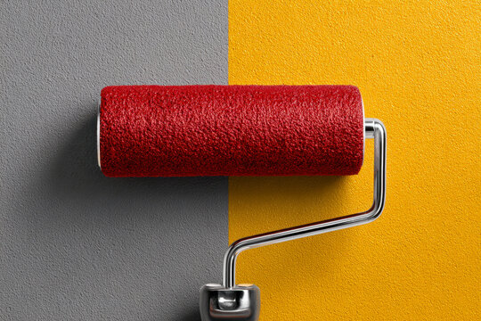 Paint roller applying vibrant golden yellow color over gray wall surface symbolizing transformation and creative home improvement concept