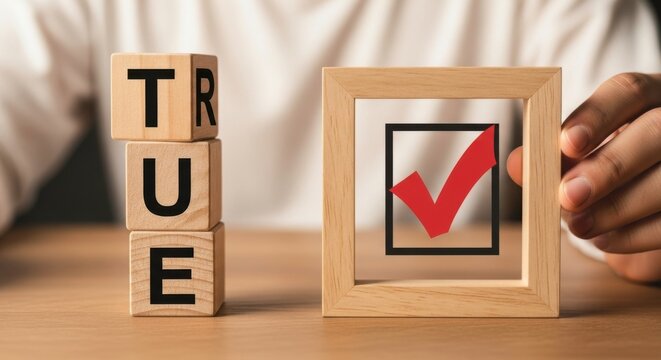 Wooden blocks spelling true next to a wooden frame with a red check mark inside it on table