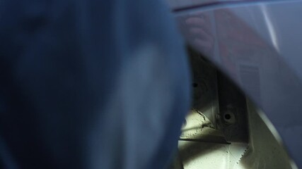 The master removes the plug under the wing and behind the wheel of the car with a hand tool. Preparing to replace the fuel filter. Home self-repair of the car