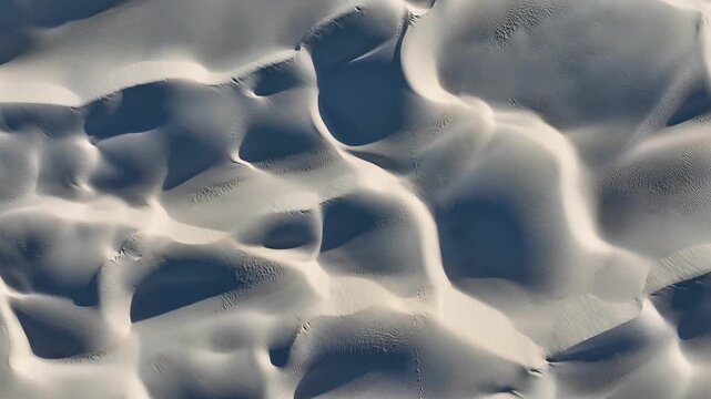 Aerial view of undulating white sand dunes, with deep shadows creating a striking contrast, showing the natural beauty of the landscape, Perth, Western Australia, Australia.