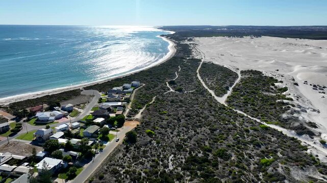 Aerial view of the contrasting turquoise ocean meeting the white sand dunes, divided by green vegetation, Lancelin, Western Australia, Australia.
