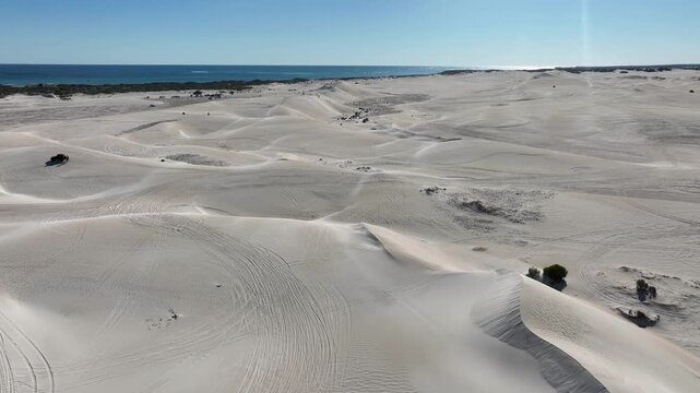 Aerial view of vast, undulating sand dunes meet the turquoise ocean, creating a stunning contrast along Beacon Road, Lancelin, Western Australia, Australia.