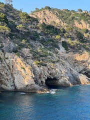 Dramatic rocky cliff with a natural cave opening and deep blue sea below