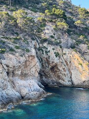 Dramatic rocky cliff with a natural cave opening and deep blue sea below