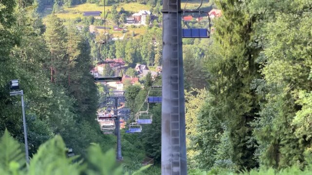 Video of a funicular ascending a mountain through lush green trees in summer, Szczawnica, Pieniny National Park, Poland. Scenic travel destination, outdoor adventure, tourism, nature landscape.